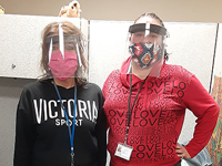 Two women with face masks and face guards posing together.