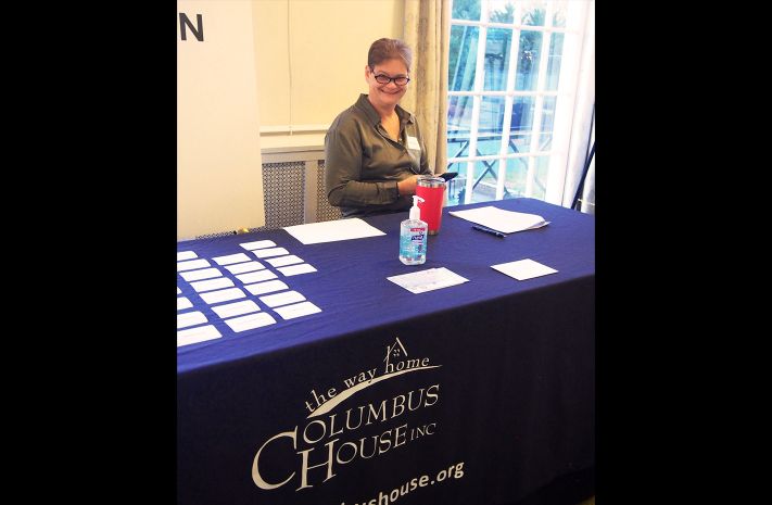 Woman smiling at a table with the Columbus House logo on the table cloth