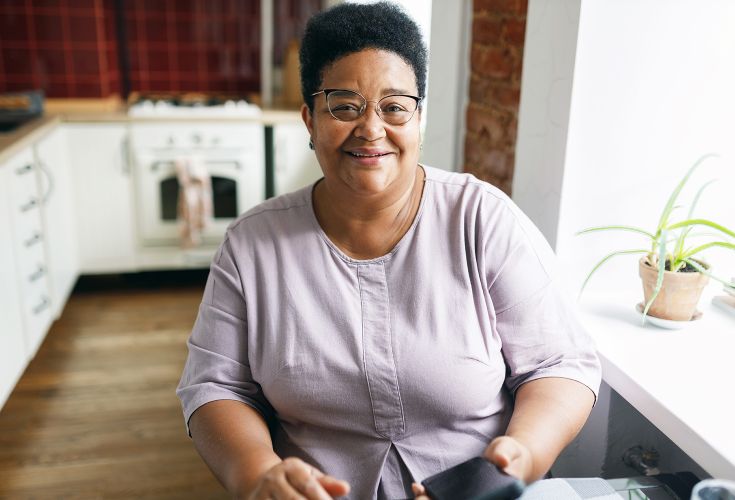 Woman sitting in kitchen, smiling