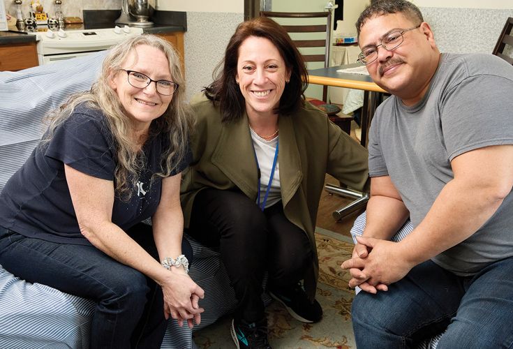 Husband and Wife posing with a social worker in an apartment