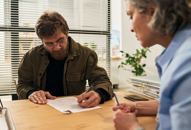Man sitting down with a woman while signing documents