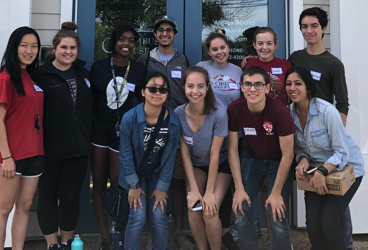 Group of volunteers posing together in front of the entrance of a Columbus House building