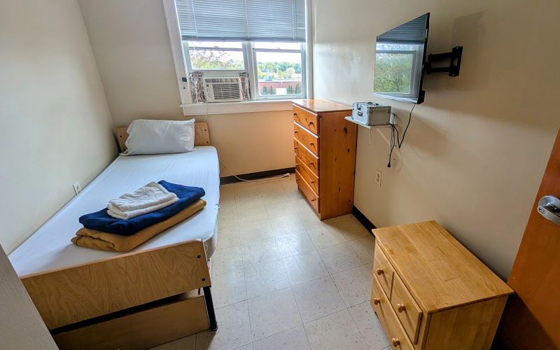Interior room with a bed, dresser, nightstand, and a TV mounted to the wall