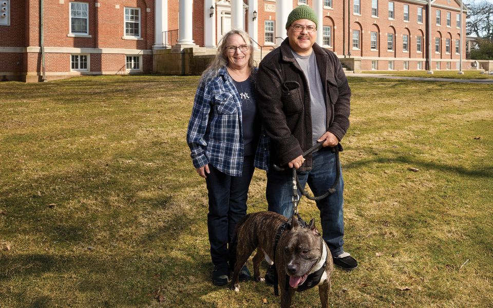 Patti and Angel posing together outside with their dogs